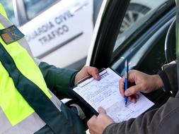 Un Guardia Civil de Tráfico pone una multa a un conductor por hablar por el teléfono movil. /Archivo