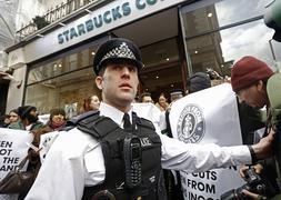 Un policía controla las protestas en un Starbucks en Londres. / Reuters