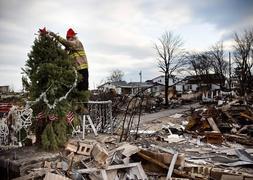 Un bombero coloca un adorno en un árbol en la zona calcinada. / Reuters