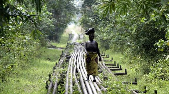 Una mujer camina sobre un oleoducto en una zona del Delta del Níger 