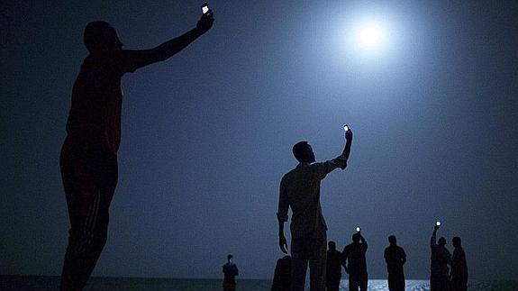 Inmigrantes africanos buscando cobertura para sus teléfonos móviles en la orilla de Yibuti. 