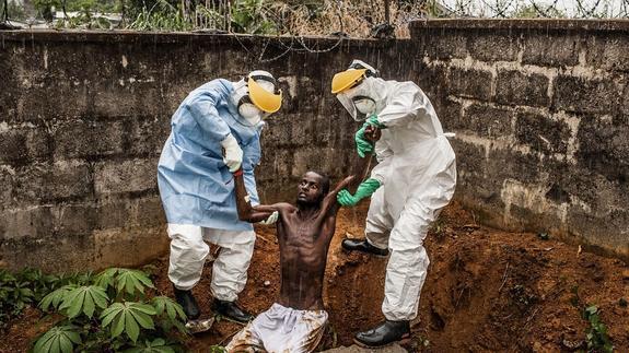 Dos sanitarios ayudan a un enfermo que se ha escapado de un centro de Sierra Leona. 