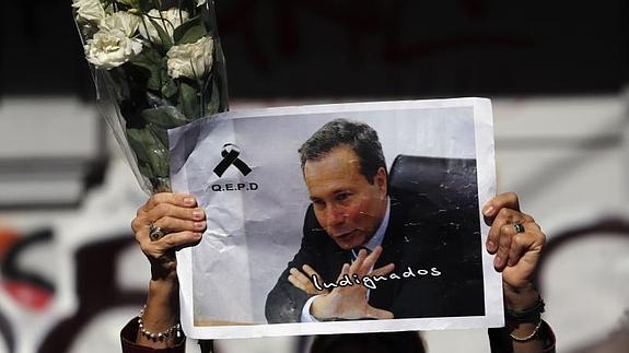 Una mujer sostiene una fotografía de Alberto Nisman en un homenaje.