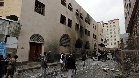 Varias personas observan el lugar del ataque de un coche bomba cerca de una mezquita chií en Saná.