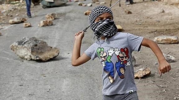Un niño palestino arroja piedras a las tropas israelíes. 