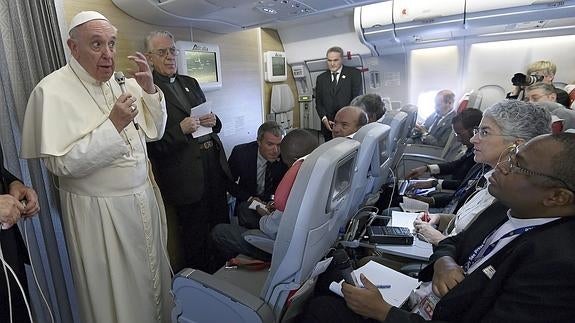 El papa Francisco (i) se dirige a los periodistas durante el vuelo que lo traslada desde Bangui hasta Roma.