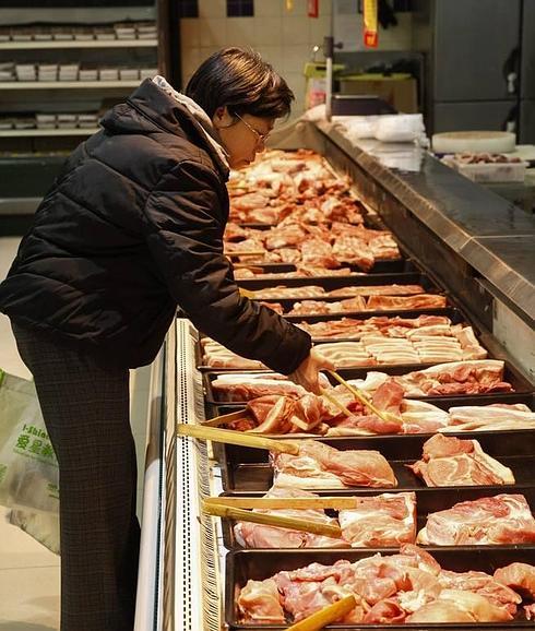 Una persona escoge carne en un supermercado.