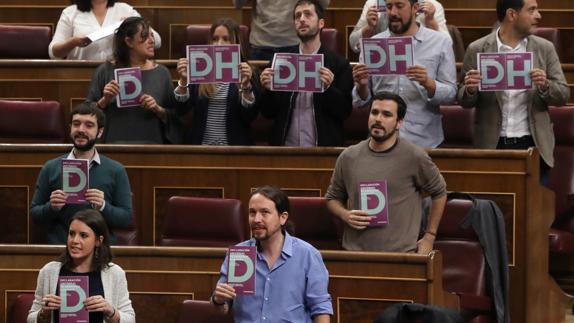 Diputados de Unidos Podemos protestan exhibiendo carteles con las iniciales DH, de Derechos Humanos.