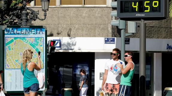 Dos turistas se fotografían ante un termómetro en Valencia.