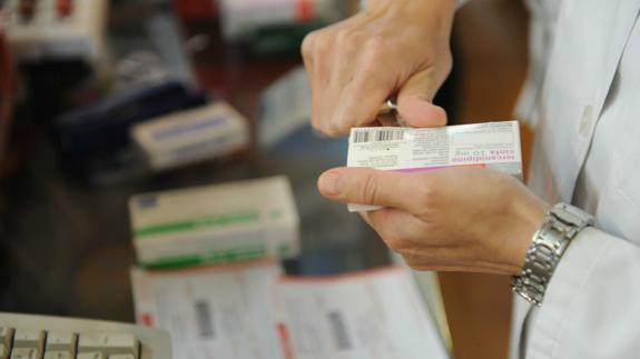 Un farmacéutico corta el cupón precinto de una caja de medicamentos.