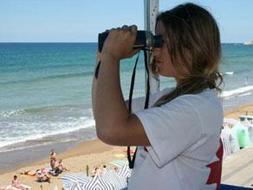 Una socorrista vigilando a los bañistas con prismaticos desde una de las cinco atalayas de la playa de Zarautz. [AMAXKAR]