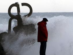 Un hombre observa como una ola rompe en el 'Peine del Viento', [EFE/Javier Etxezarreta]