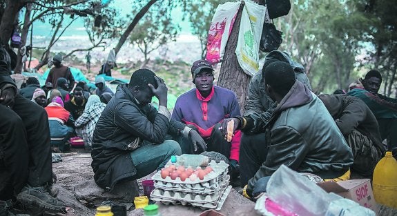 Los inmigrantes acampados en el monte Gurugú, cerca de Melilla, comienzan a preparar la comida de la jornada, con el comienzo de la noche, como obliga el Ramadán.