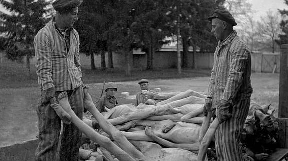 Los soldados estadounidenses, tras la liberación del campo, supervisan a varios prisioneros mientras éstos cargan cadáveres. 