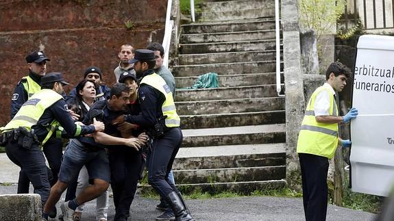 Agentes de la Ertzaintza contienen a un allegado del fallecido.