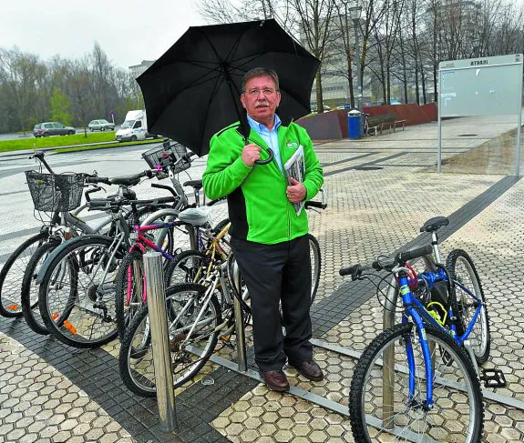 José Luis Arrieta se protege de la lluvia junto a unas bicicletas.