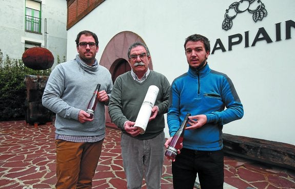 Mikel, Miguel y Egoitz posan con dos de las botellas de Bizi-Goxo y su estuche cilíndrico.