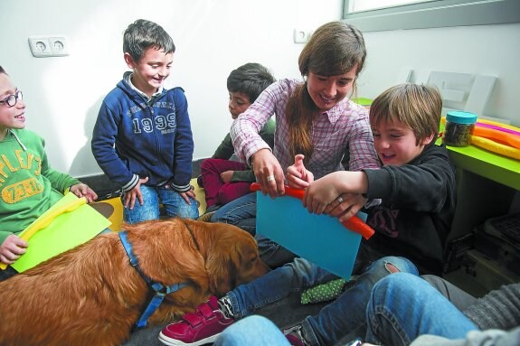 Lukas, en el centro, repone fuerzas mientras Nela ayuda a uno de los chavales durante una de las actividades del taller. 