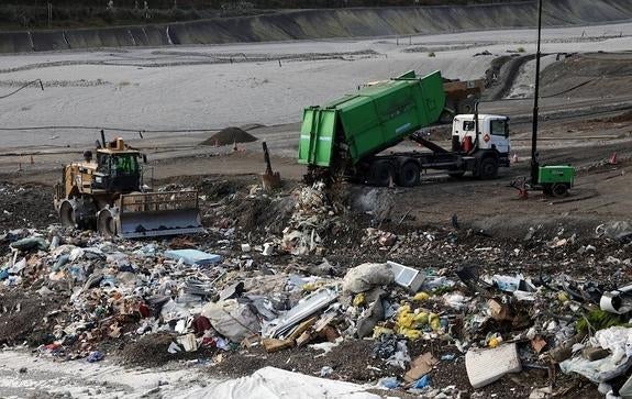 Un camión vierte residuos ante la máquina compactadora en el vertedero cántabro de Meruelo.