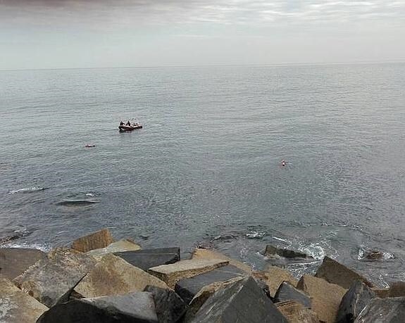 Una lancha junto a las rocas desde las que la víctima cayó al agua. 