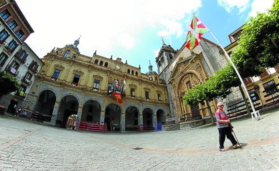 Una vecina pasea por la plaza Gudari de Hernani, presidida por la Casa Consistorial y la parroquia de San Juan.