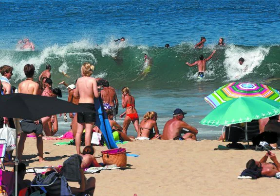 Los bañistas saltan las olas ayer en una playa de La Zurriola llena de gente. 