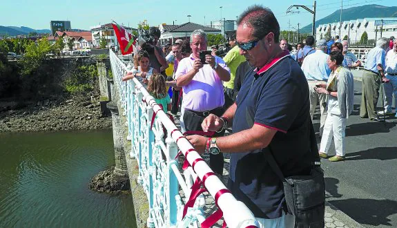 Un centenar de ciudadanos se sumaron ayer al acto de atar lazos rojos en la barandilla del puente Avenida para recordar a quienes lo cruzaron en 1936.