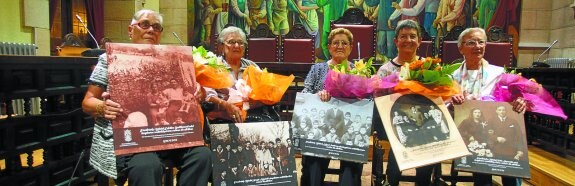 Allegados a los cinco homenajeados, con las fotografías de sus familiares y los ramos que les entregó el alcalde. 