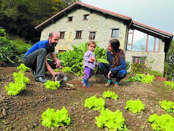 La pequeña de la casa, Ilargi, con sus padres Eguzkiñe y Oliver en el huerto del agroturismo. 