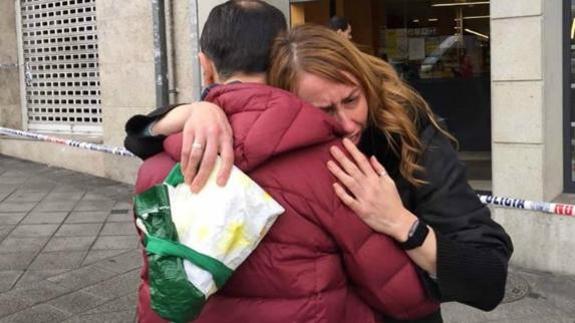 Dos personas se abrazan frente al supermercado en el que han tenido lugar los disparos