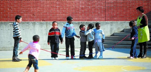 Varios estudiantes inmigrantes juegan en el patio de un colegio.