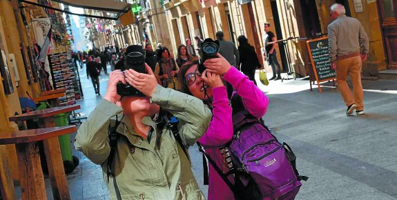 Dos turistas en la calle Mayor donostiarra inmortalizan su visita a la capital guipuzcoana.