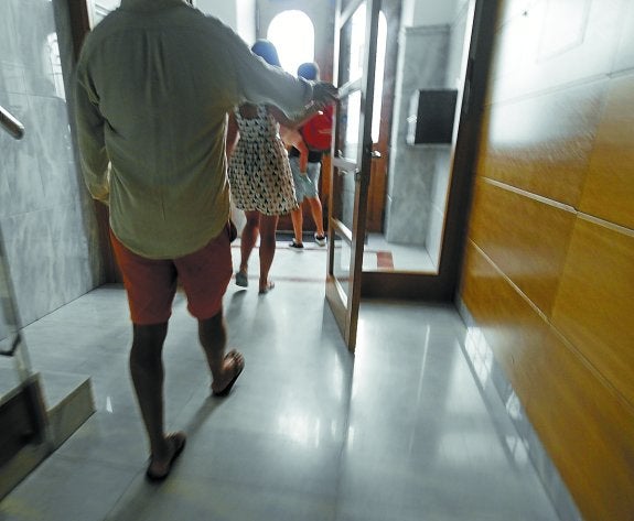 Una familia de turistas sale del portal en el que ha alquilado un apartamento en vacaciones.