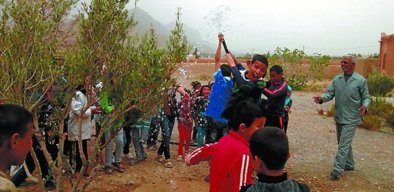 Un grupo de niños de Ait-Innou juega con la manguera que colocaron en el grifo recién instalado, ante la mirada divertida de su profesor.