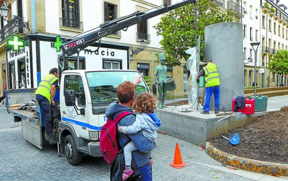 Dos operarios colocan el nuevo panel de bronce con la letra de la Marcha de San Sebastián. 