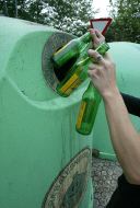 Una persona deposita botellas de vidrio en el contenedor. [FRAILE]
