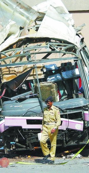 Un policía, junto a los restos del autobús objeto del atentado. ::                             AFP