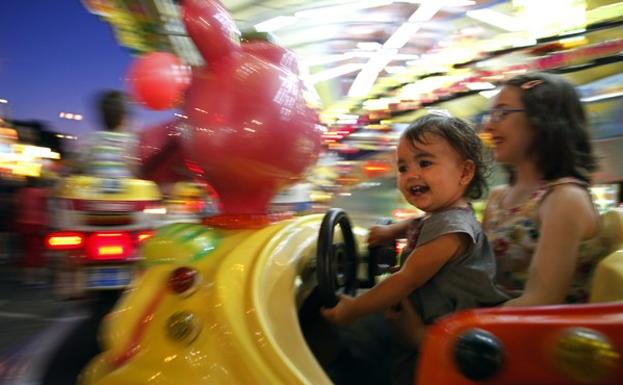 Unas niñas disfrutan de las atracciones infantiles durante unas fiestas.