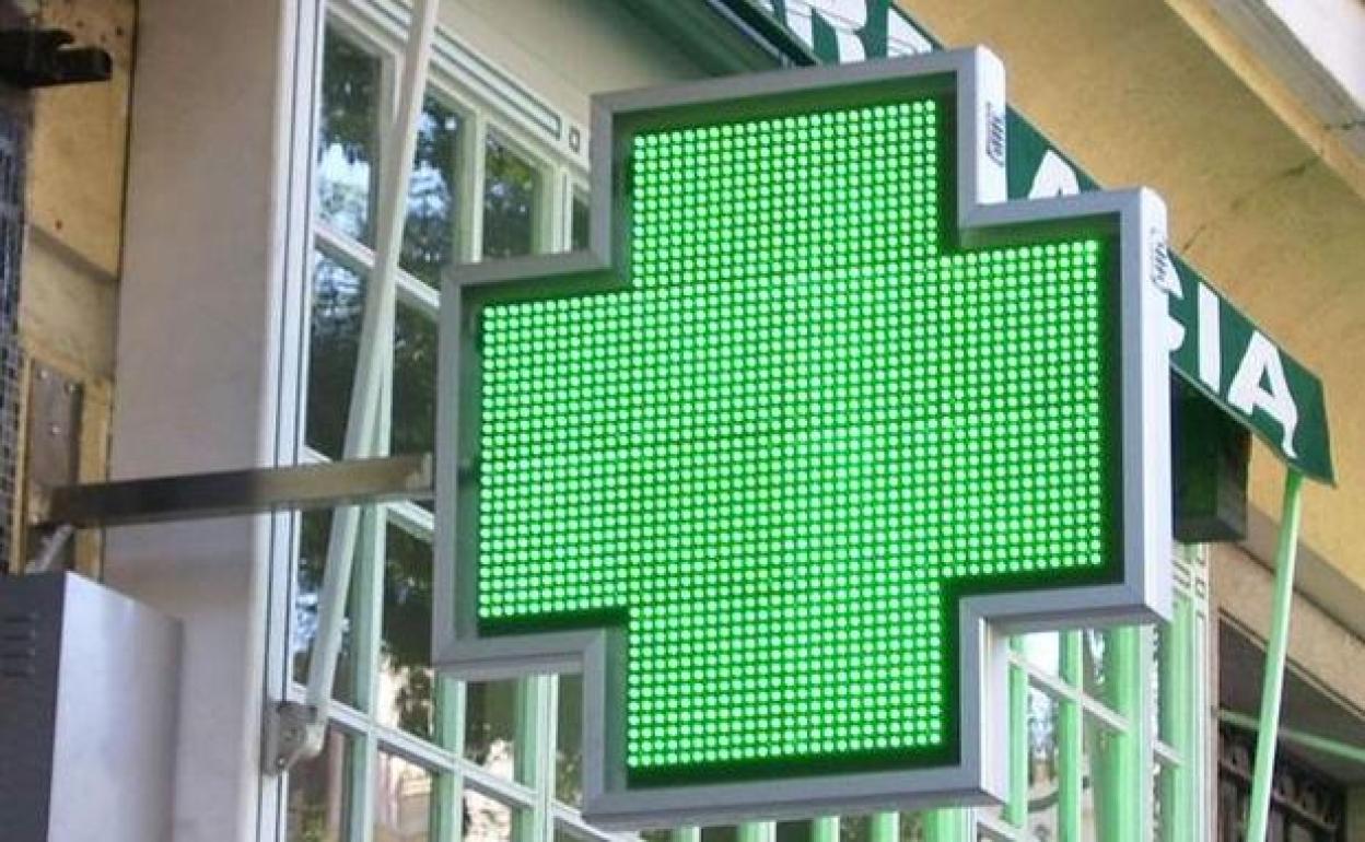 Imagen del logo iluminado de una farmacia.