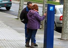 Dos personas introducen monedas en un parquímetro de la ORA en Ponferrada.