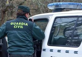 Un agente de la Guardia Civil junto a un coche patrulla, en una imagen de archivo.