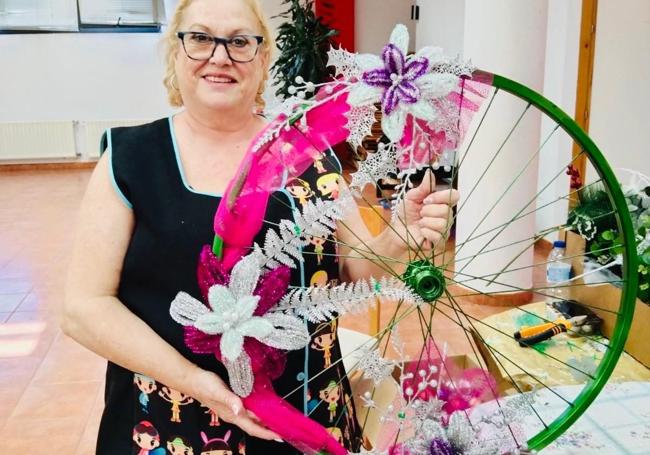 Una vecina muestra uno de los trabajos de decoración navideña aprovechando una llanta de la rueda de una bicicleta.