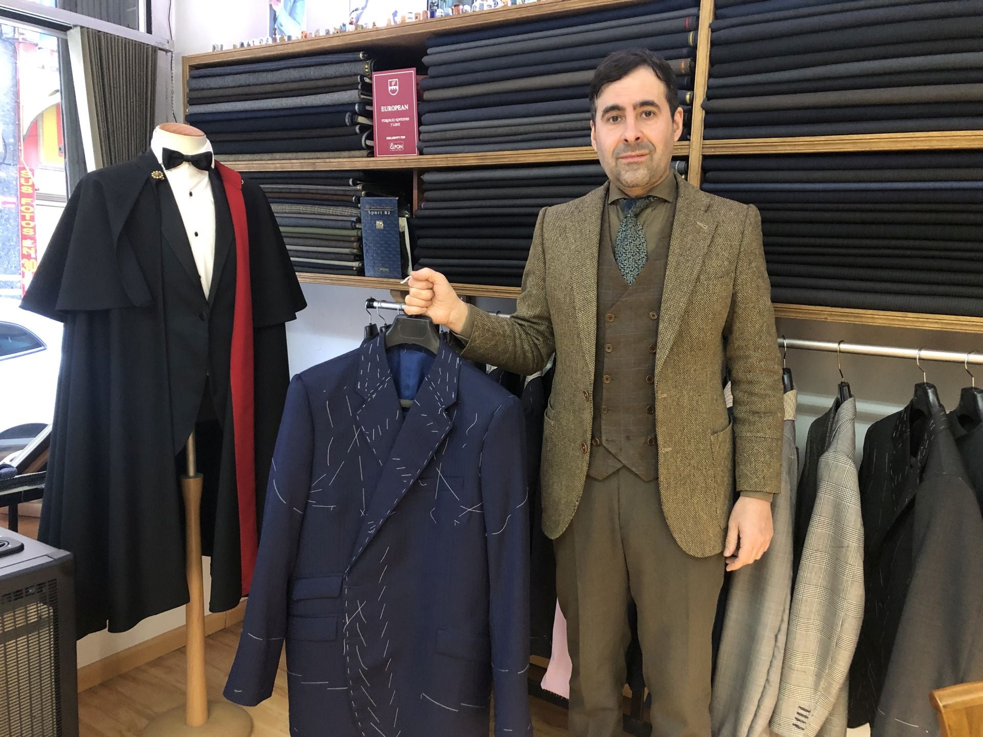 El sastre ponferradino muestra una blazer en confección junto a una capa española.