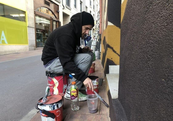El artista donostiarra, Asier Vera, durante la realización de uno de sus trabajos creativos en la fachada de una casa en la calle Real de Ponferrada