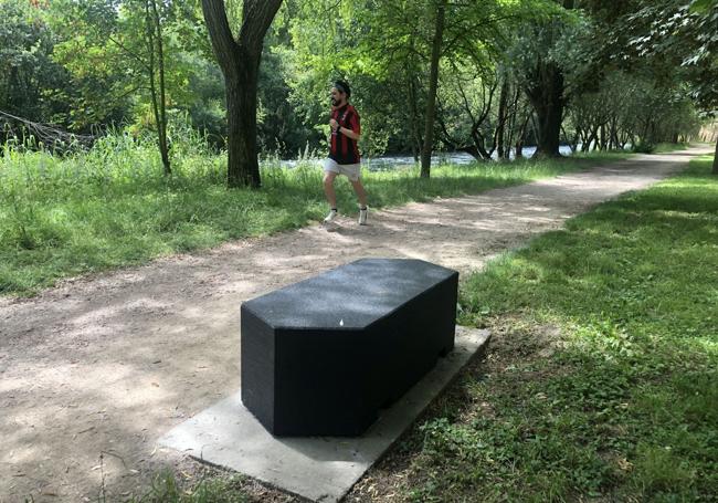 Un corredor pasa junto a uno de los peculiares bancos que pueblan el paseo del río Sil.