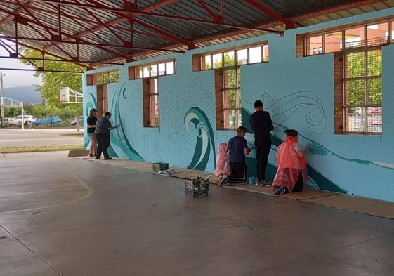 Alumnos del CEE Bergidum pintan el mural en el patio interior del colegio.