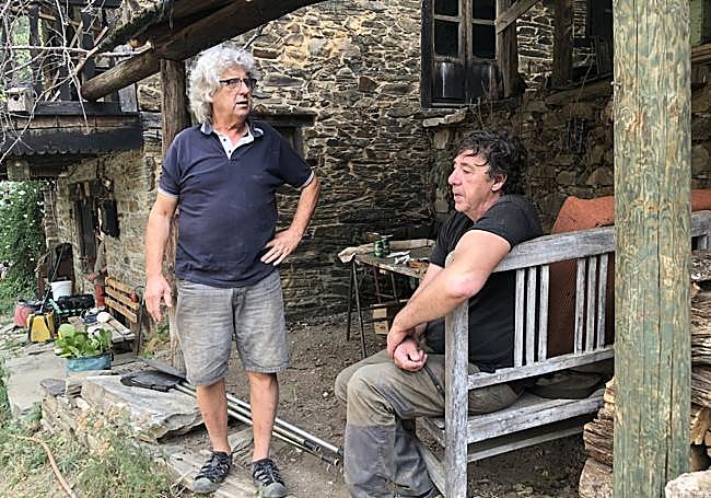 Dos de los habitantes de Palacios del Sil conversan mientras contemplan la intensa nube de humo instalada frente a sus casas.