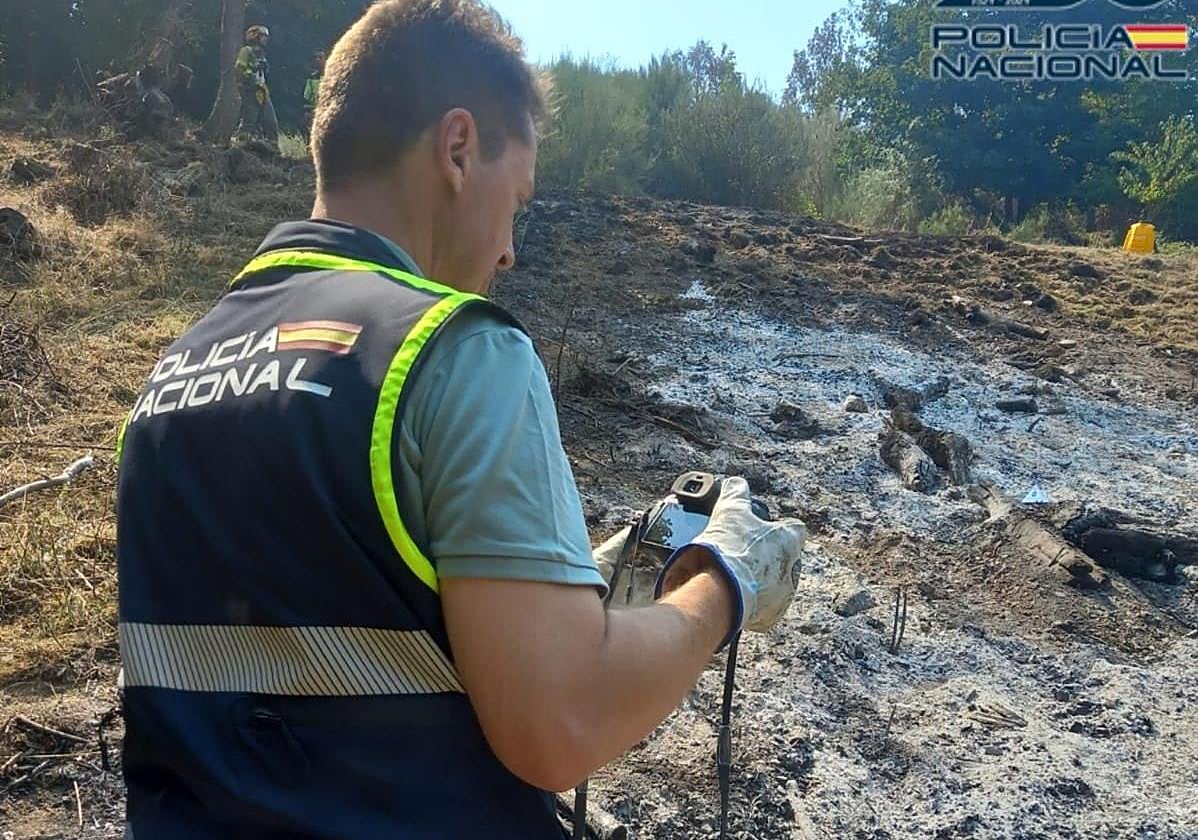 Un agente de la Policía Nacional realiza la inspección técnico-policial en la zona del incendio en Bouzas.