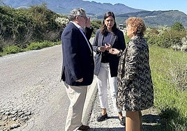La concejala de Fomento (C) y el pedáneo de Santo Tomás de la Ollas (I) conversan con una técnico municipal junto a la carretera de acceso a La Llanada.