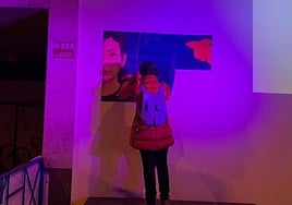 Una de las participantes en la protesta coloca una de las piezas en papel del antiguo mural de Nevenka en el espacio donde fue borrado